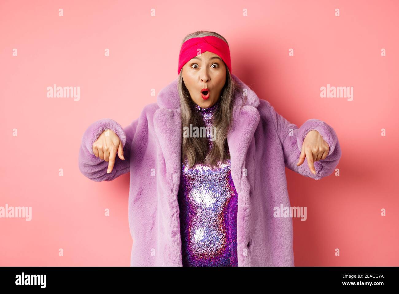 Mode- und Shopping-Konzept. Beeindruckt asiatische weibliche Zeigefinger nach unten und Blick aufgeregt bei der Kamera, zeigt genial promo Angebot, stehen über Stockfoto