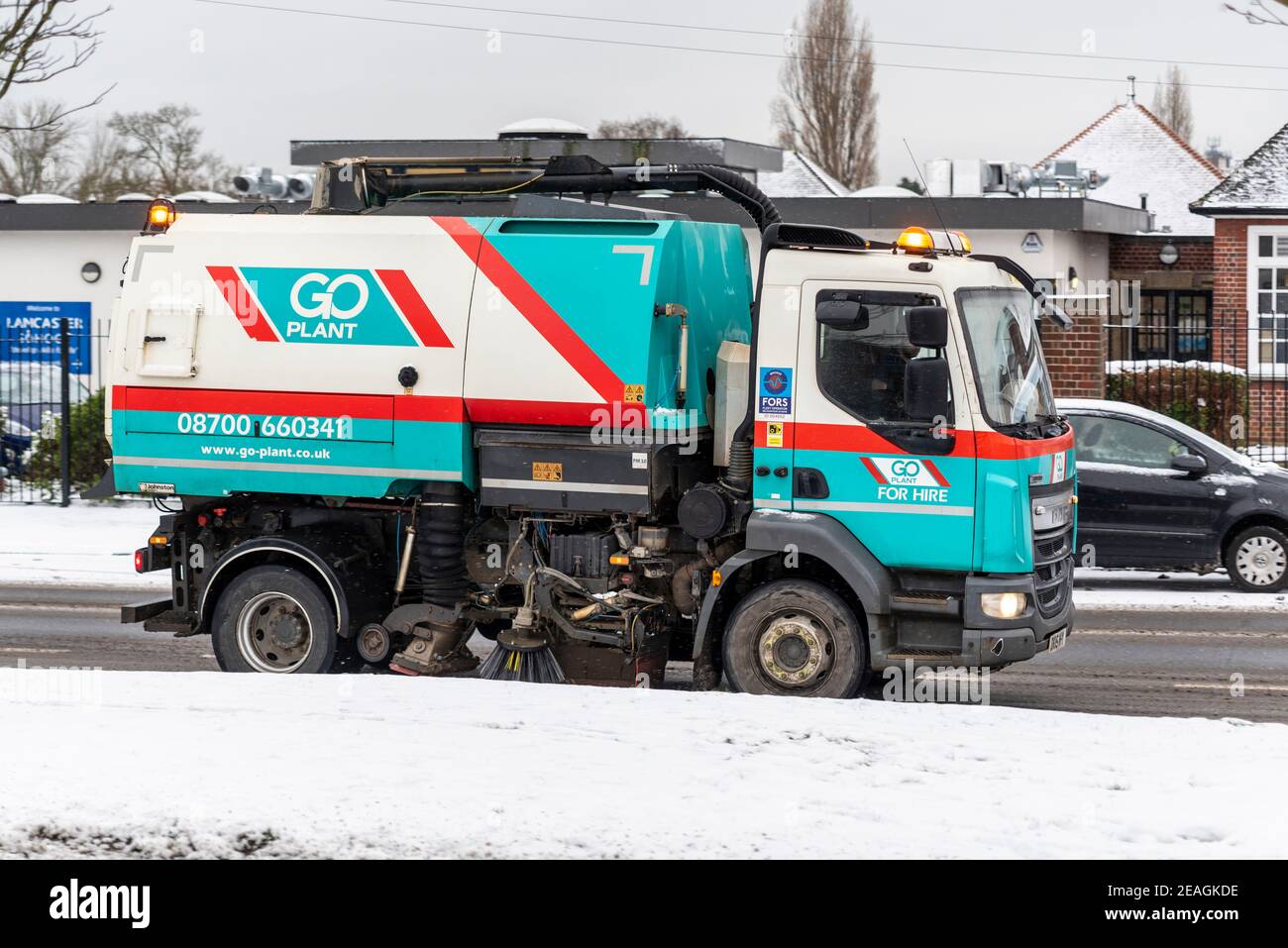 Go Plant Road Kehrmaschine auf eisiger Straße in Southend on Sea, Essex, Großbritannien, mit Schnee von Storm Darcy. Gemietete Industriefahrzeuge. Stockfoto