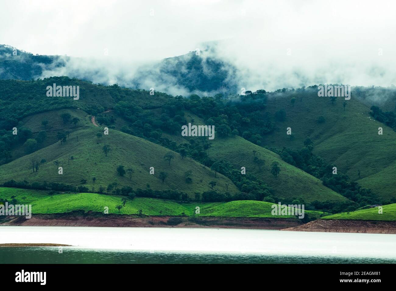 Berge neben einem See mit Wolken verdunsten auf dem Hügel nach einem Niederschlag am Nachmittag. Landschaft des Lago de Furnas, bei Capitó Stockfoto