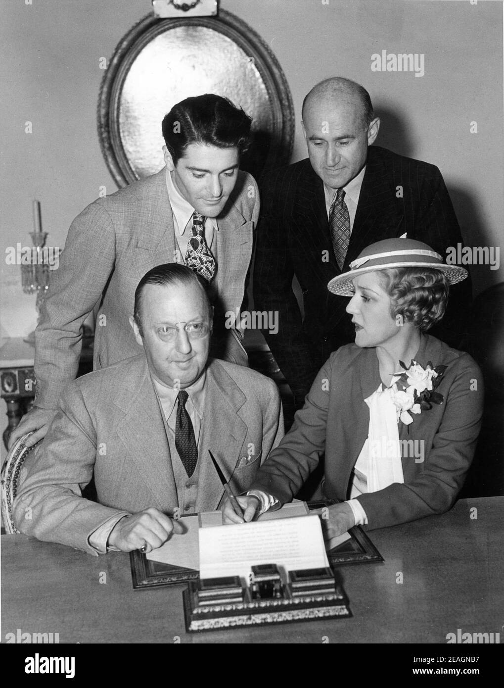 Die gemeinsamen Produzenten JESSE L. LASKY und MARY PICKFORD unterzeichnen bei ihrem Pickfair zu Hause einen Vertrag für ihren neuen Film ONE RAINY AFTERNOON (veröffentlicht am 1936. Mai), während der Hauptdarsteller FRANCIS LEDERER und der United Artists-Produzentenkollege SAMUEL GOLDWYN sich anschauen Stockfoto