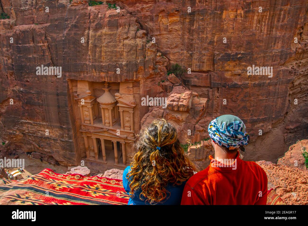 Junges Paar sitzt an einem Aussichtspunkt auf Al Khazneh Grab auch Schatzkammer in Petra, Jordanien genannt Stockfoto