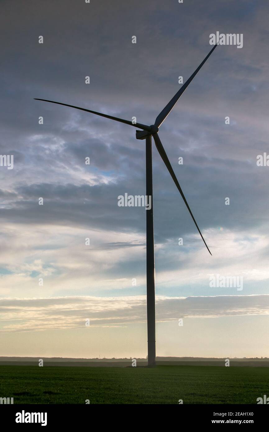 Silhouette Windturbine Offshore Windmühle aus Eisen mit Klingen auf dem Feld gegen einen blauen Himmel mit Wolken auf Sonnenuntergang, alternative Elektrizität preservi Stockfoto