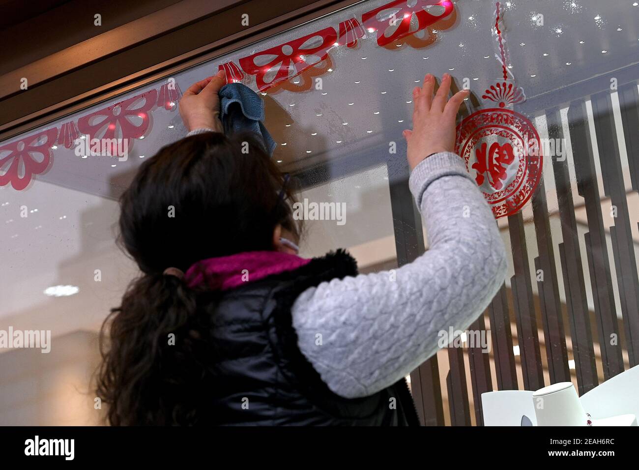 New York, USA. Februar 2021, 09th. Eine Frau schmückt das Fenster eines Juwelierladens Tage vor Beginn des chinesischen Neujahrsfestes in Manhattans Chinatown-Viertel, New York, NY, 9. Februar 2021. Mitglieder der chinesischen Gemeinschaft und anderer asiatischer Kulturen feiern das chinesische Mondneujahr, das Jahr der OX, das am 12. Februar beginnt und bis Januar 31st als wichtigster Feiertag in China gilt. (Foto von Anthony Behar/Sipa USA) Quelle: SIPA USA/Alamy Live News Stockfoto