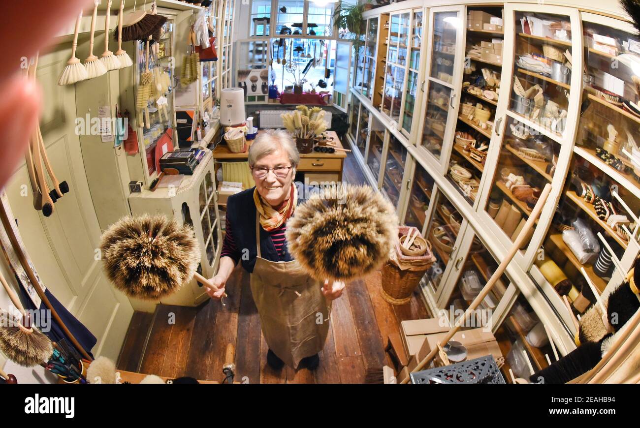08. Februar 2021, Sachsen-Anhalt, Naumburg: In ihrer kleinen Bürstenmanufaktur, die auch als Verkaufsraum dient, hält die 81-jährige Bürstenmanufaktur Ursula Römer zwei Federstauber in den Händen. Obwohl ihr Laden wegen der Pandemie geschlossen ist, kommen derzeit viele Bestellungen aus ganz Deutschland per Telefon oder schriftlich für große und kleine Besen, Spinnenfeger, Federstauber oder sogar Wand- und Deckenbesen. In ihrem traditionellen Laden, den ihr Urgroßvater 1885 eröffnete, stellt die 81-Jährige ihre Pinsel und Besen mit einer Vielzahl von Borsten auf alte, traditionelle Weise mit der Hand her Stockfoto