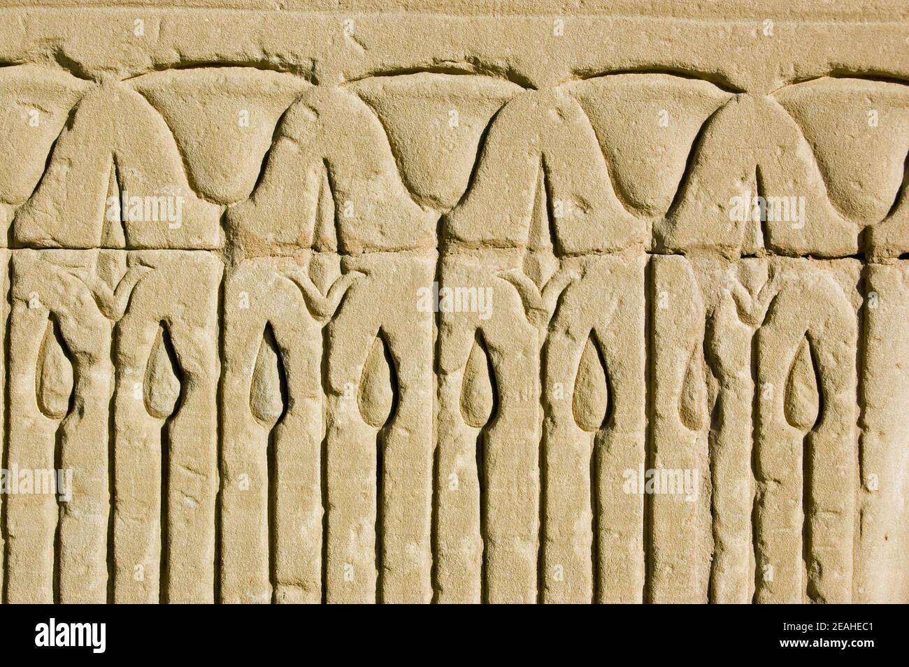 Nahaufnahme eines alten ägyptischen Steinfrieses mit Lotusblüten in einem Schilfbett. Äußere Wand des Tempels von Horus, Edfu, Ägypten. Stockfoto