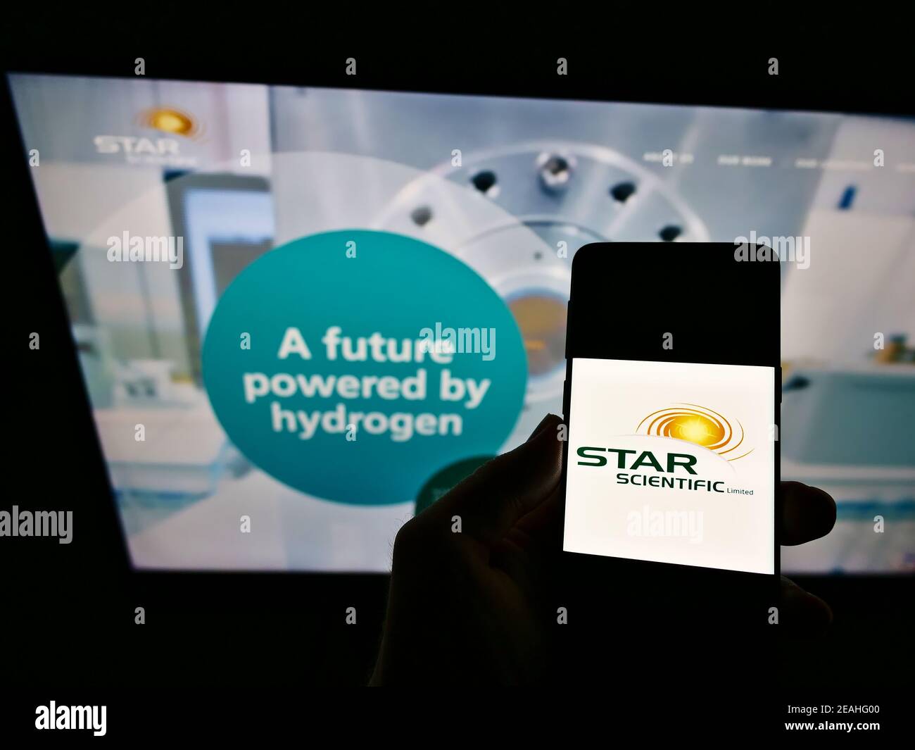 Person, die Mobiltelefon mit dem Logo der australischen Wasserstoffgesellschaft Star Scientific Limited auf dem Bildschirm vor der Webseite hält. Konzentrieren Sie sich auf die Telefonanzeige. Stockfoto
