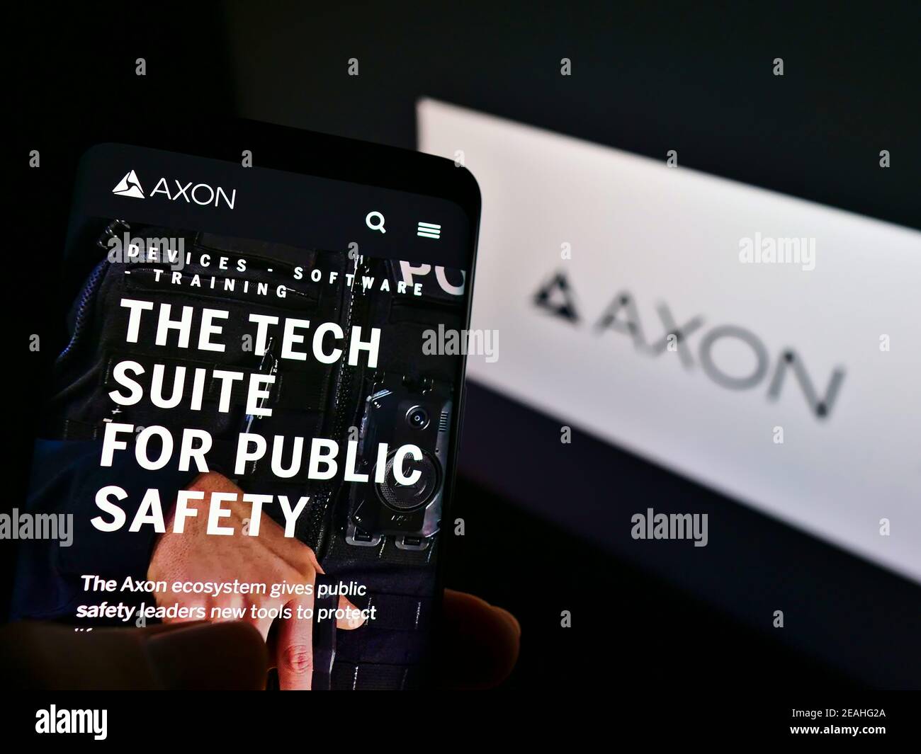 Person, die Smartphone mit Website des amerikanischen Waffenproduzenten Axon Enterprise Inc. Auf dem Bildschirm vor dem Logo hält. Fokus auf der Mitte des Telefondisplays. Stockfoto