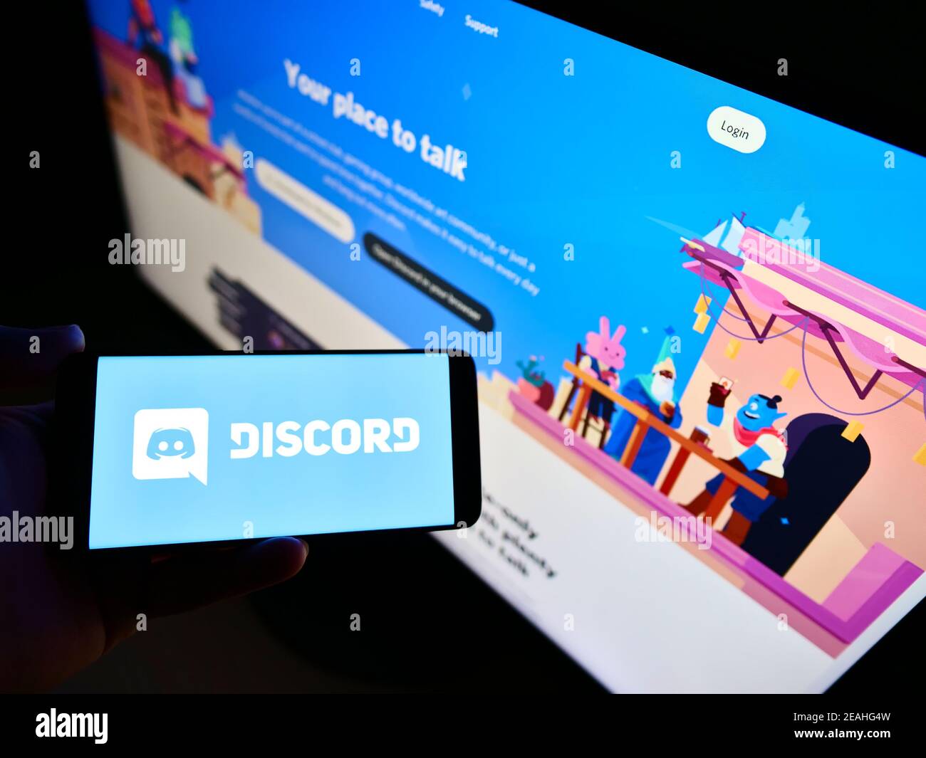 Person mit Mobiltelefon und Logo der von Discord Inc. Entwickelten US-Kommunikationsplattform auf dem Bildschirm vor der Webseite. Konzentrieren Sie sich auf die Telefonanzeige. Stockfoto