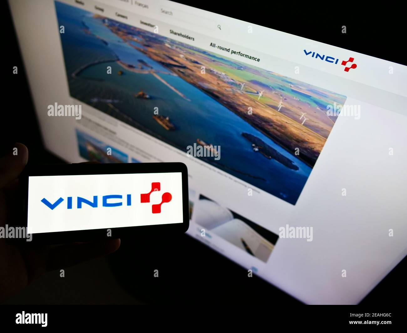Person, die Smartphone mit Logo der französischen Konzessionen und Bauunternehmen Vinci S.A. auf dem Bildschirm vor der Website hält. Konzentrieren Sie sich auf die Telefonanzeige. Stockfoto