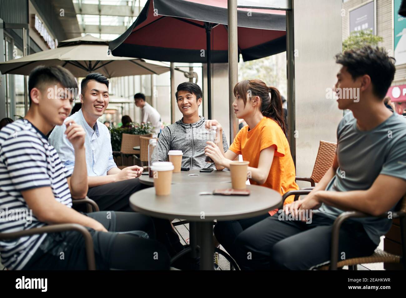 Junge asiatische Erwachsene Männer und Frau sitzen chatten entspannen in Café im Freien Stockfoto