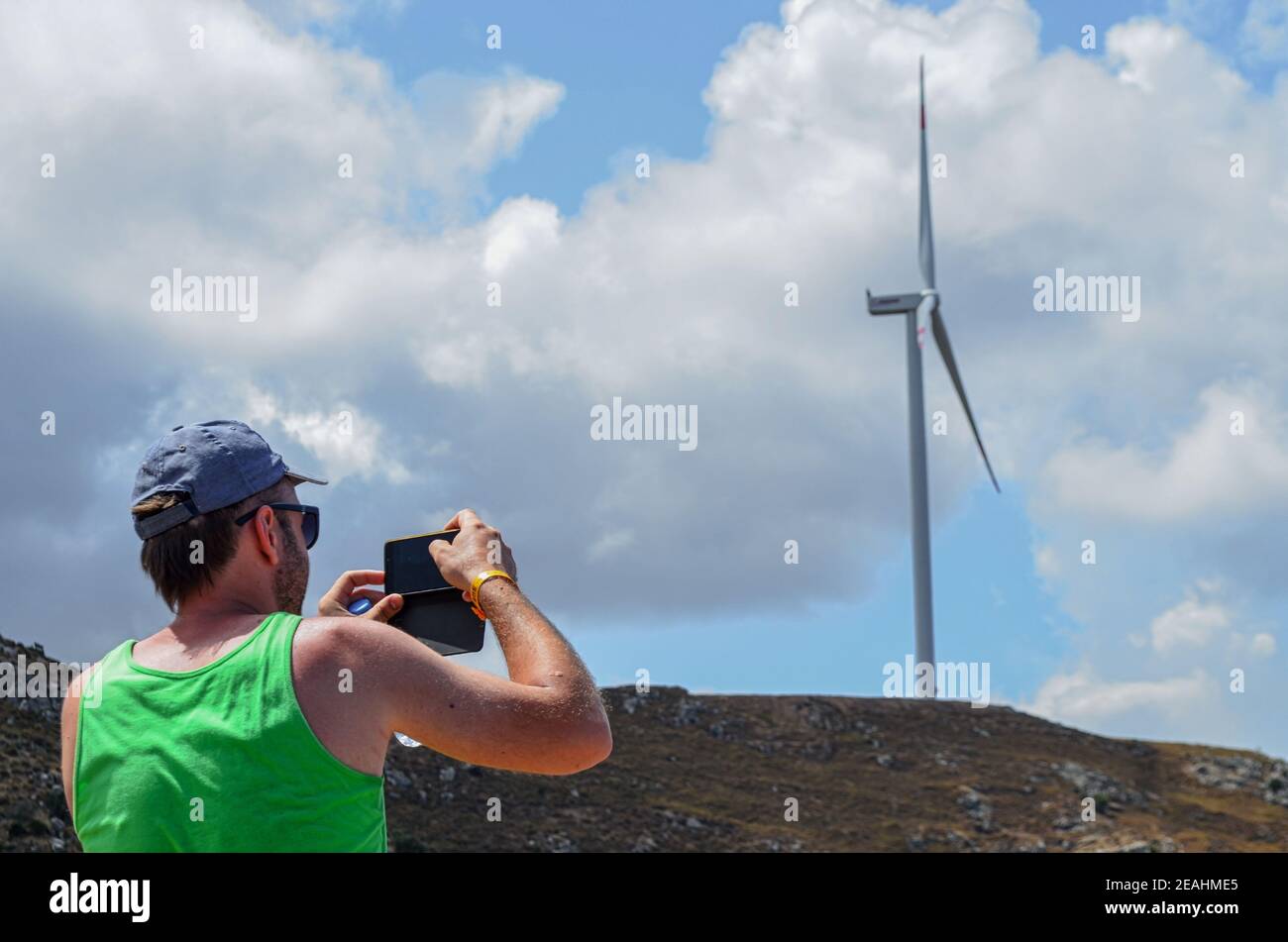 Der Mensch erfasst auf dem Smartphone eine Windturbine auf dem Berg Mit Wolken Stockfoto