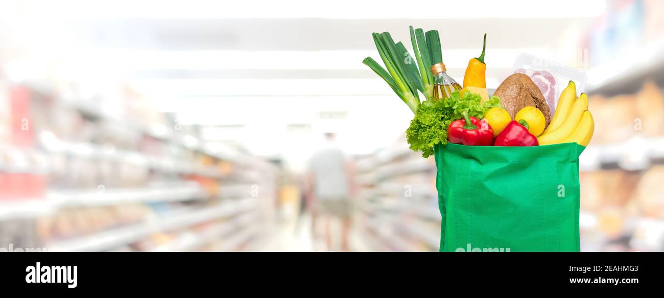 Lebensmittel und Lebensmittel im wiederverwendbaren grünen Einkaufstasche im Supermarkt Banner-Hintergrund mit Kopierbereich Stockfoto