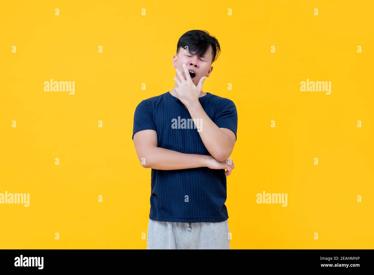 Müde schläfrig asiatischen Mann gähnend mit Hand bedeckt Mund leiden Von Schlaflosigkeit Stockfoto
