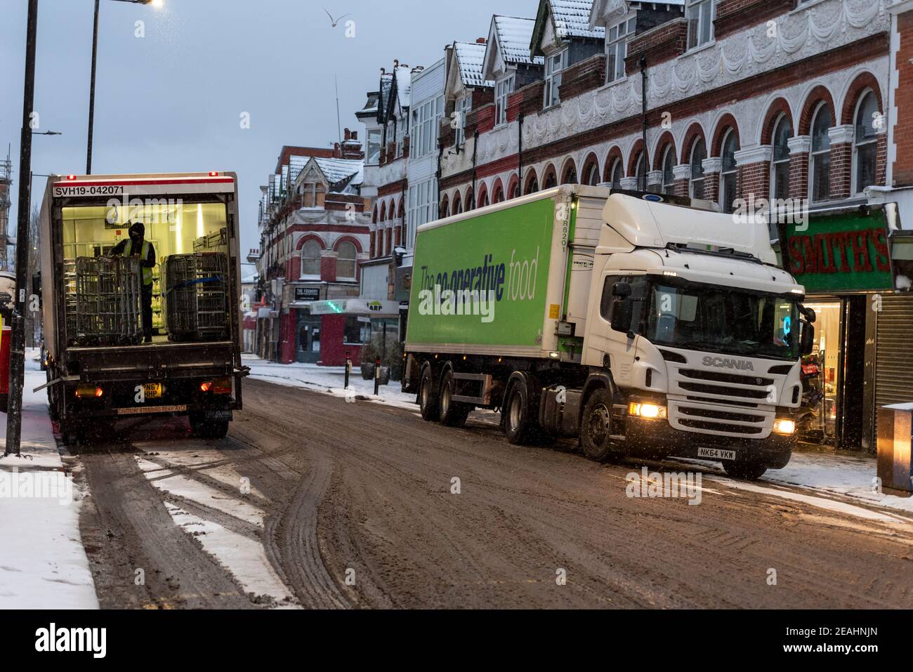 Lieferung von Lebensmitteln in den frühen Morgenstunden für Co-op-Supermarkt in Hamlet Court Road, Westcliff on Sea, Essex, UK, mit Schnee von Storm Darcy. Schlüsselarbeiter entladen Stockfoto