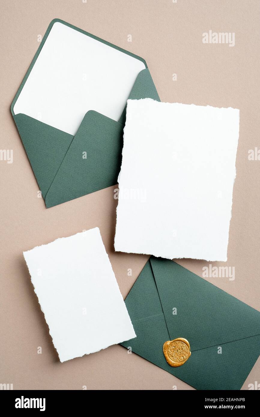Elegante Hochzeit Einladungskarten Mockups und grüne Umschläge auf braunem Hintergrund. Flach liegend, Draufsicht, Kopierbereich. Stockfoto