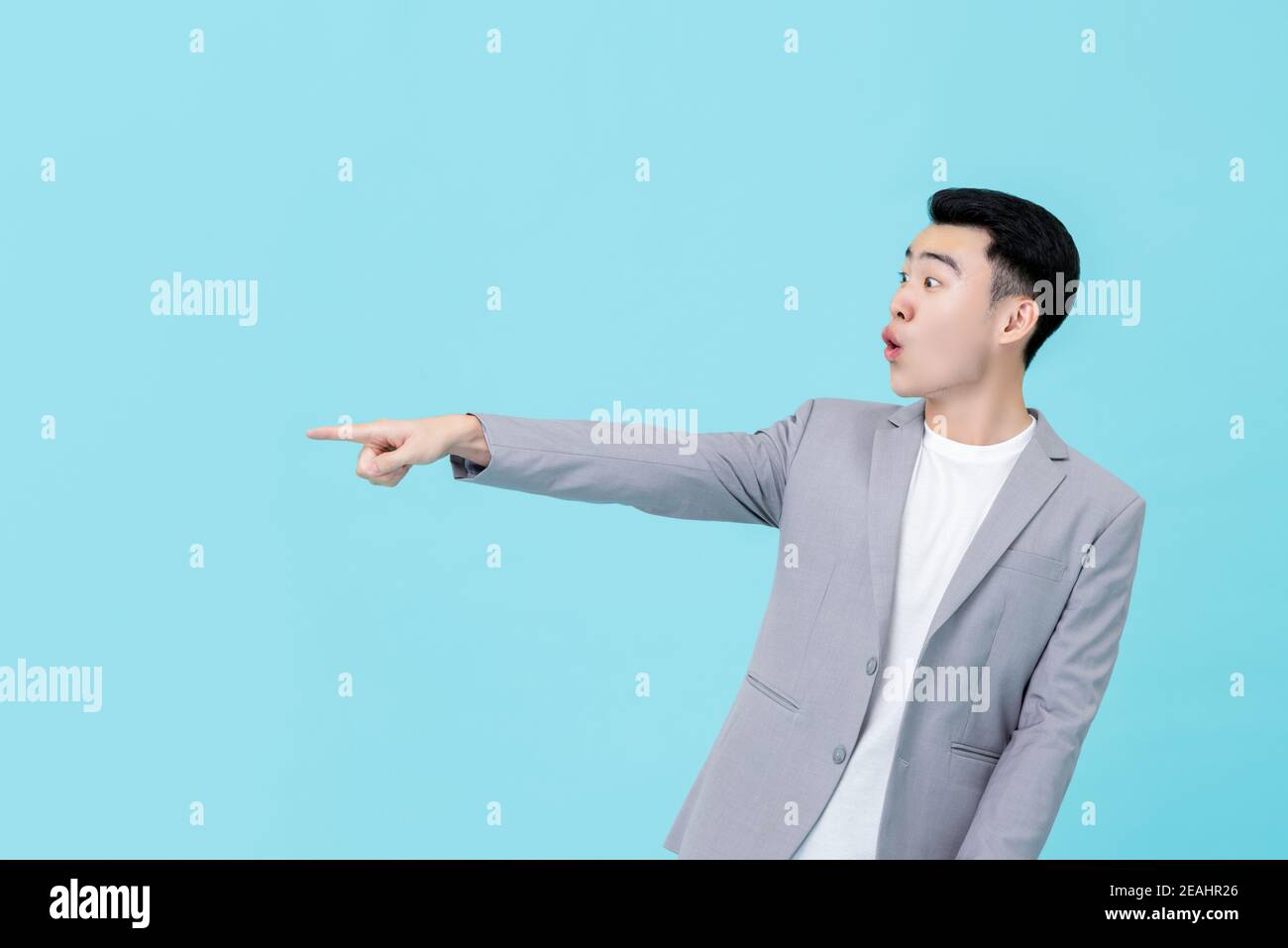 Junge gut aussehende asiatische Geschäftsmann in smart casual Kleidung suchen überrascht Und staunend Zeigehand, um den Raum isoliert auf Licht zu kopieren Blauer Hintergrund Stockfoto