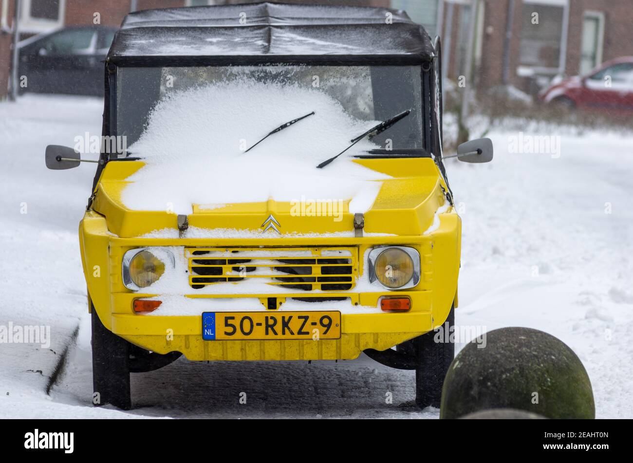 Boskoop, Niederlande, 7. FEBRUAR 2021: Verschneite gelbe Citroen Mehari Auto in der Winterszene Straße geparkt Stockfoto