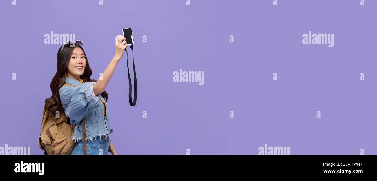 Attraktive junge asiatische Frau Touristen nehmen Selfie glücklich mit Kamera Isoliert auf violettem Bannerhintergrund mit Kopierbereich Stockfoto
