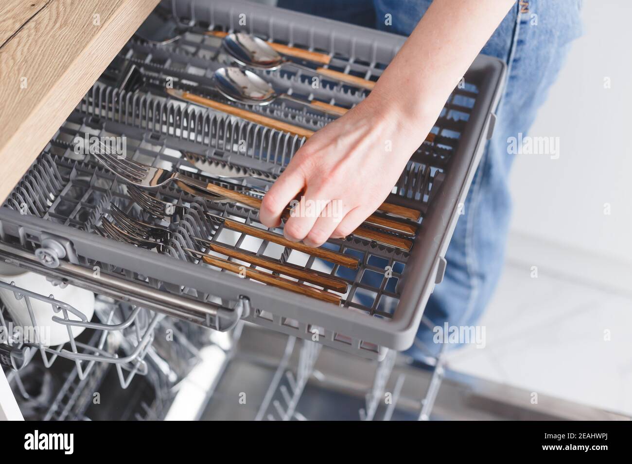 Frau stellt Besteck in die Spülmaschine. Stockfoto