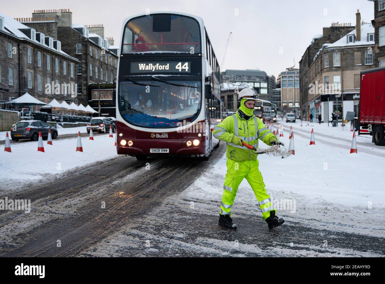 Edinburgh, Schottland, Großbritannien. Februar 2021, 10. In Großbritannien setzt sich der große Frost fort, und der schwere Schnee über Nacht und Morgen bringt den Verkehr auf vielen Straßen im Stadtzentrum zum Stillstand. PIC; Arbeiter verteilen Salz von Hand am Kreisverkehr an der Lothian Road und Leith Walk. . Iain Masterton/Alamy Live Nachrichten Stockfoto