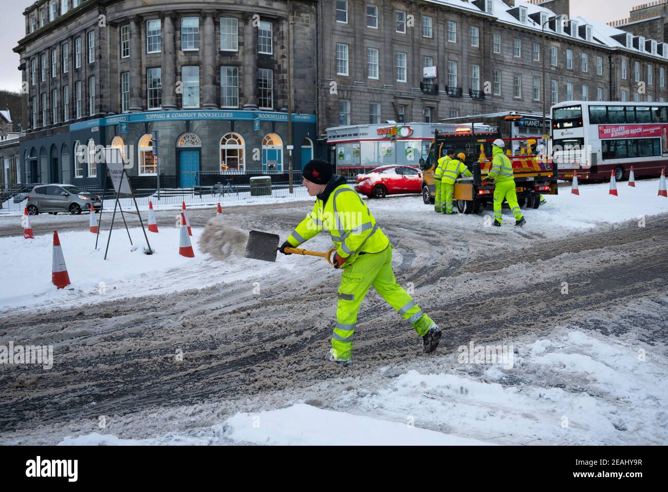 Edinburgh, Schottland, Großbritannien. Februar 2021, 10. In Großbritannien setzt sich der große Frost fort, und der schwere Schnee über Nacht und Morgen bringt den Verkehr auf vielen Straßen im Stadtzentrum zum Stillstand. PIC; Arbeiter verteilen Salz von Hand am Kreisverkehr an der Lothian Road und Leith Walk. . Iain Masterton/Alamy Live Nachrichten Stockfoto
