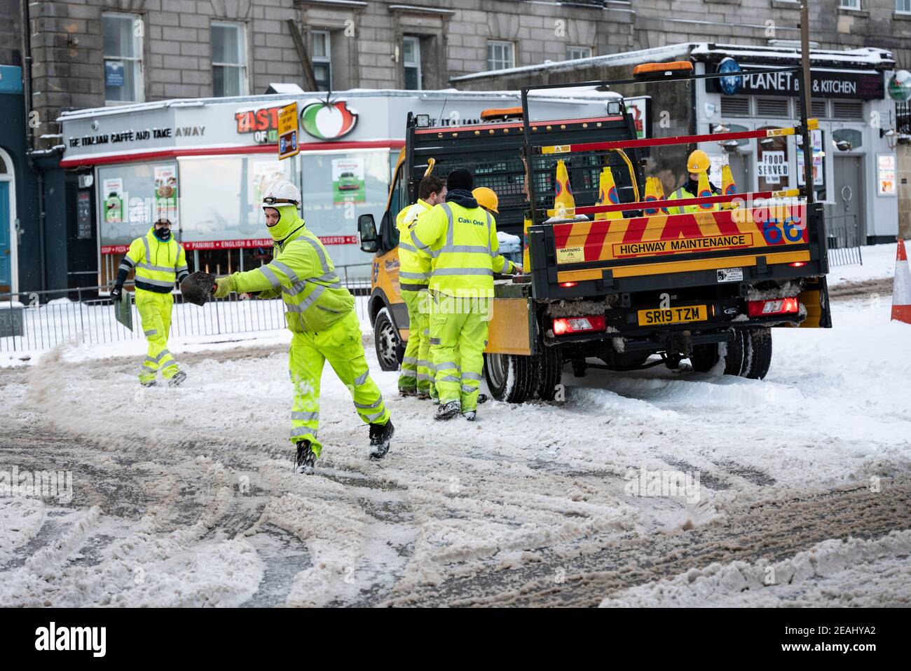 Edinburgh, Schottland, Großbritannien. Februar 2021, 10. In Großbritannien setzt sich der große Frost fort, und der schwere Schnee über Nacht und Morgen bringt den Verkehr auf vielen Straßen im Stadtzentrum zum Stillstand. PIC; Arbeiter verteilen Salz von Hand am Kreisverkehr an der Lothian Road und Leith Walk. . Iain Masterton/Alamy Live Nachrichten Stockfoto