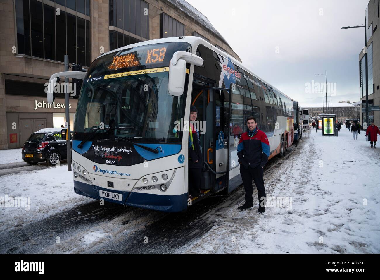 Edinburgh, Schottland, Großbritannien. Februar 2021, 10. In Großbritannien setzt sich der große Frost fort, und der schwere Schnee über Nacht und Morgen bringt den Verkehr auf vielen Straßen im Stadtzentrum zum Stillstand. PIC; Stagecoach Busfahrer die Zeit warten auf Straße zu löschen auf Leith Walk. Iain Masterton/Alamy Live Nachrichten Stockfoto