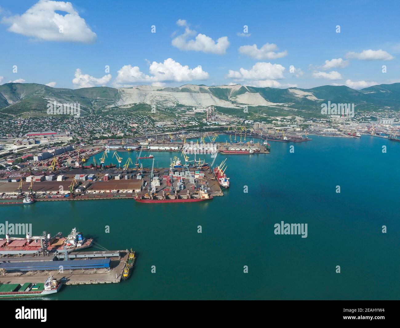 Industriehafen, Blick von oben. Hafenkrane und Frachtschiffe und Lastkähne. Verladung und Verladung von Fracht im Hafen. Blick auf den Seefrachthafen mit Blick aus der Vogelperspektive Stockfoto