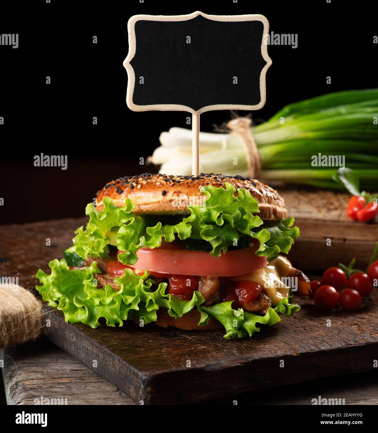 Cheeseburger mit Hackfleisch, grünem Salat und Ketchup auf einem braunen Holzbrett Stockfoto