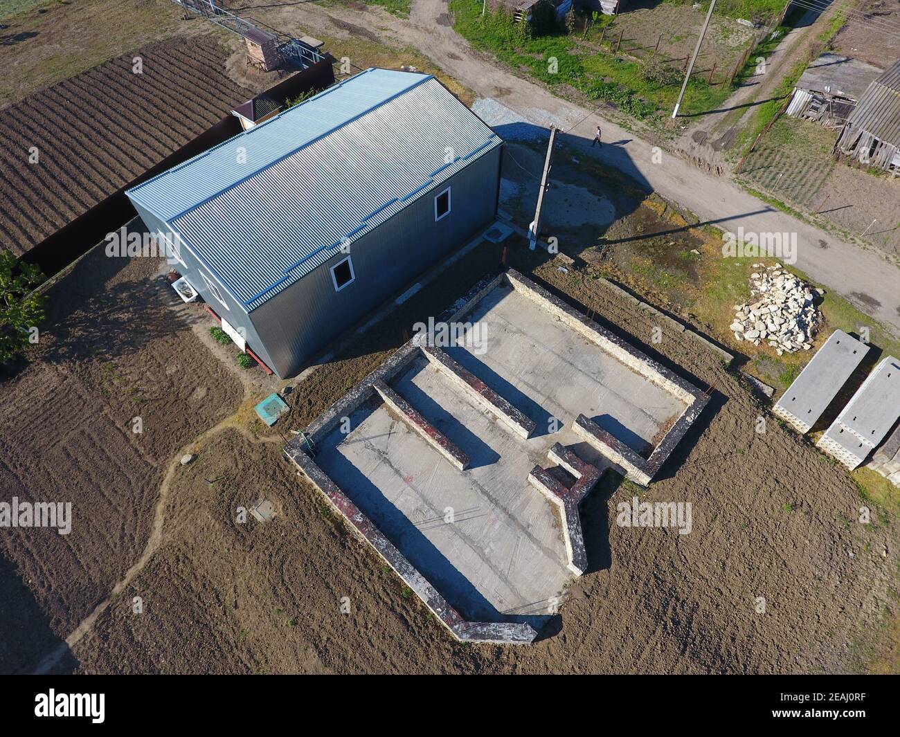 Gebäude auf dem Gelände. Hangar aus Metall Profil, gewellt. Das Fundament des Hauses. Stockfoto
