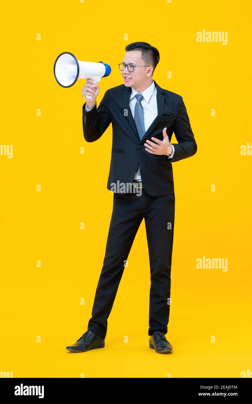Asiatische Geschäftsmann mit Megaphon über zu sagen oder etwas zu verkünden Isoliert auf gelbem Hintergrund Stockfoto