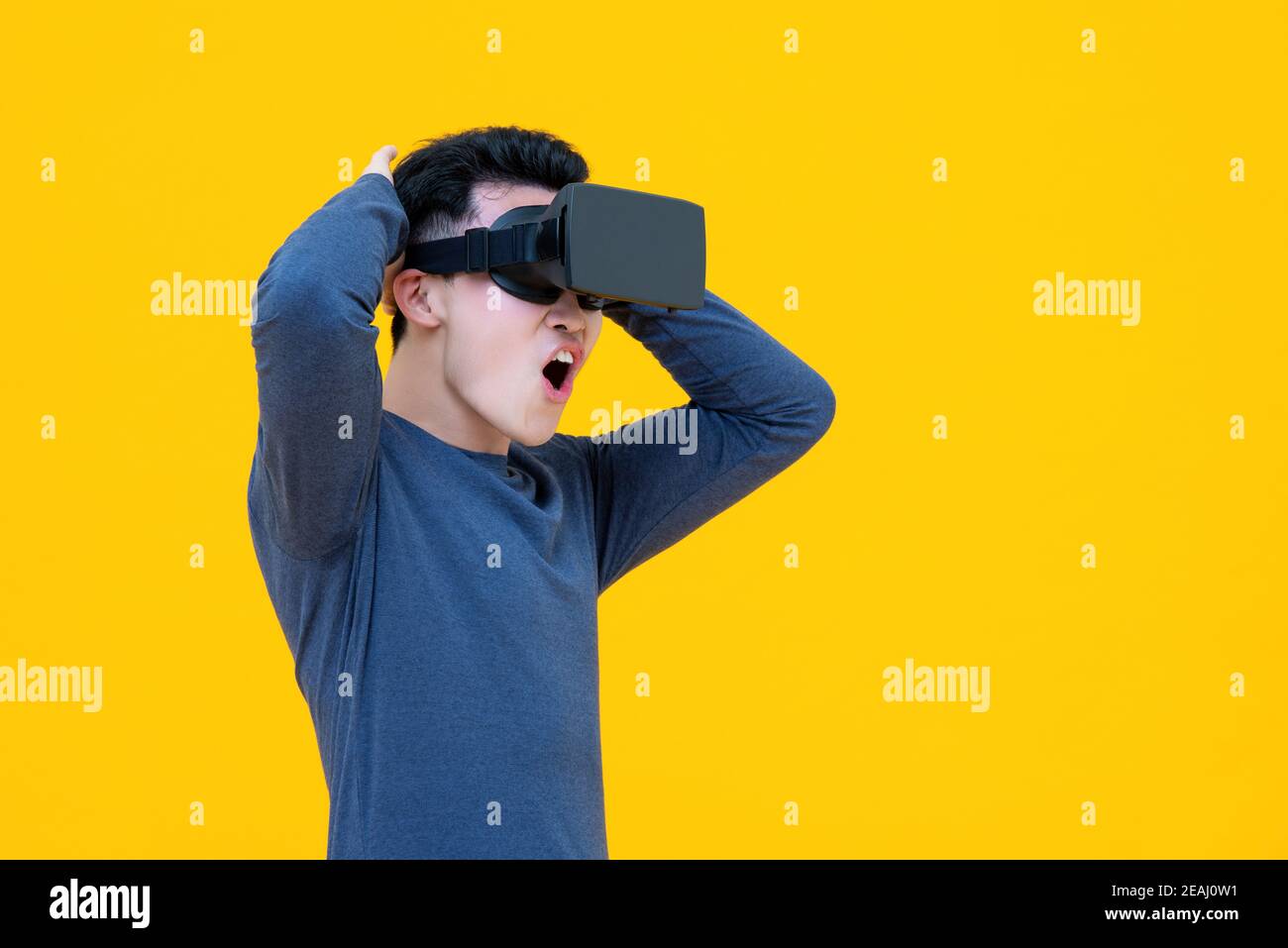 Aufgeregt asiatischen Mann genießen 3D-Simulation Video aus der virtuellen Realität oder VR-Brille auf gelbem Hintergrund Stockfoto