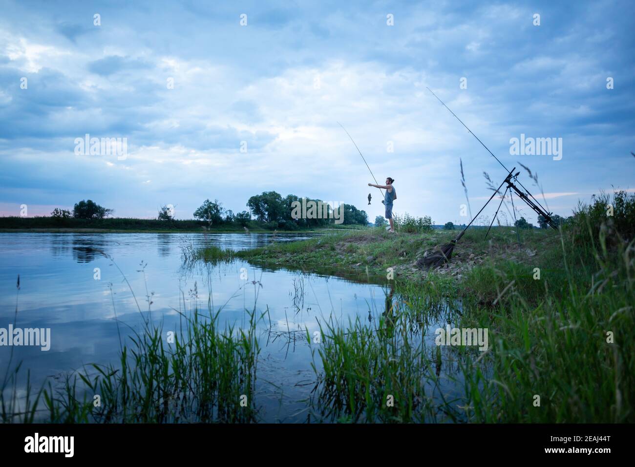 Angler auf einem Flussufer fing einen Fisch Stockfoto
