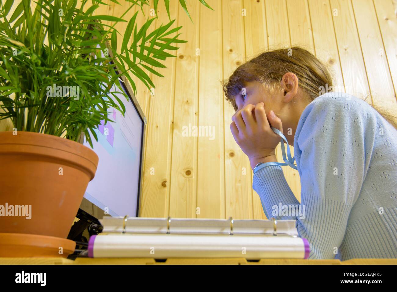 Ein Student sitzt in der Ferne vor dem Computer Lernen und schaut nachdenklich auf den Bildschirm Stockfoto