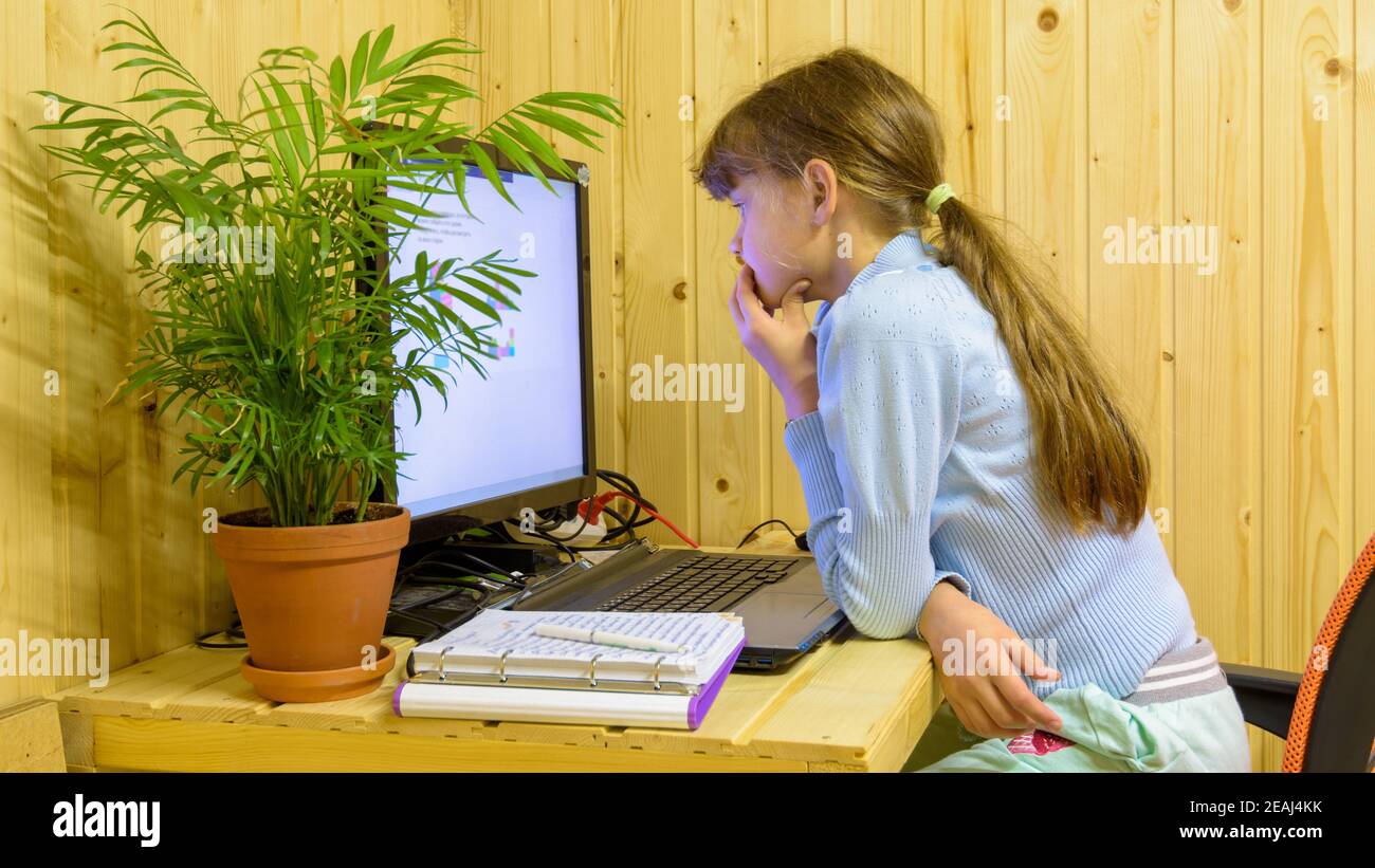 Ein Schulmädchen liest nachdenklich ein Problem in einer Online-Lektion Mit Fernunterricht Stockfoto