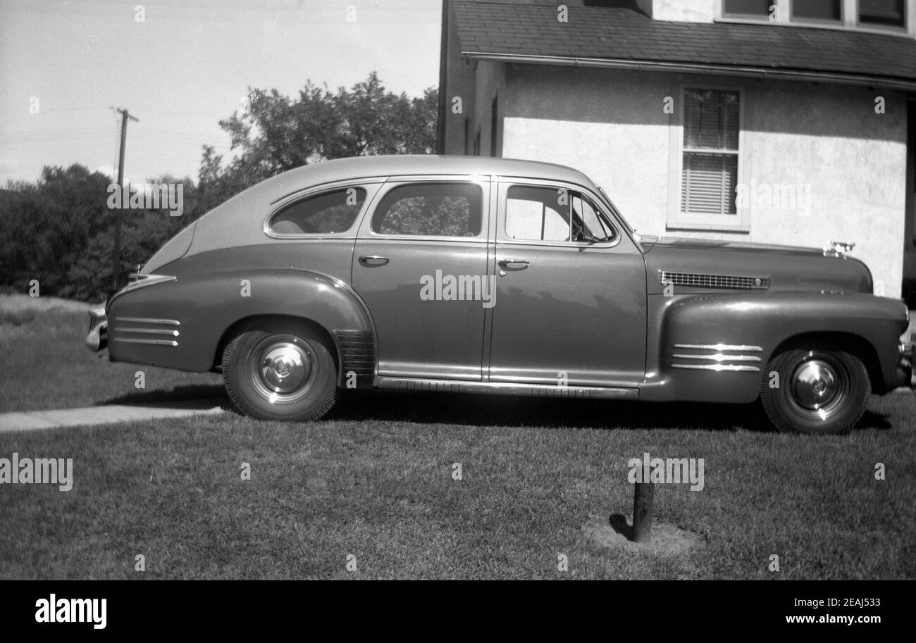 1945, historisches, elegantes amerikanisches Automobil, das auf einem Grasrand vor einem Haus geparkt ist, Oregon, USA. Stockfoto