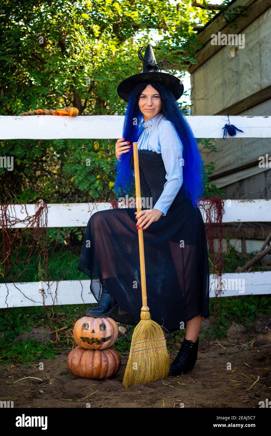 Niedliches Mädchen in einem Hexenkostüm mit Kürbissen und einem Besen auf einer Halloween Party Stockfoto
