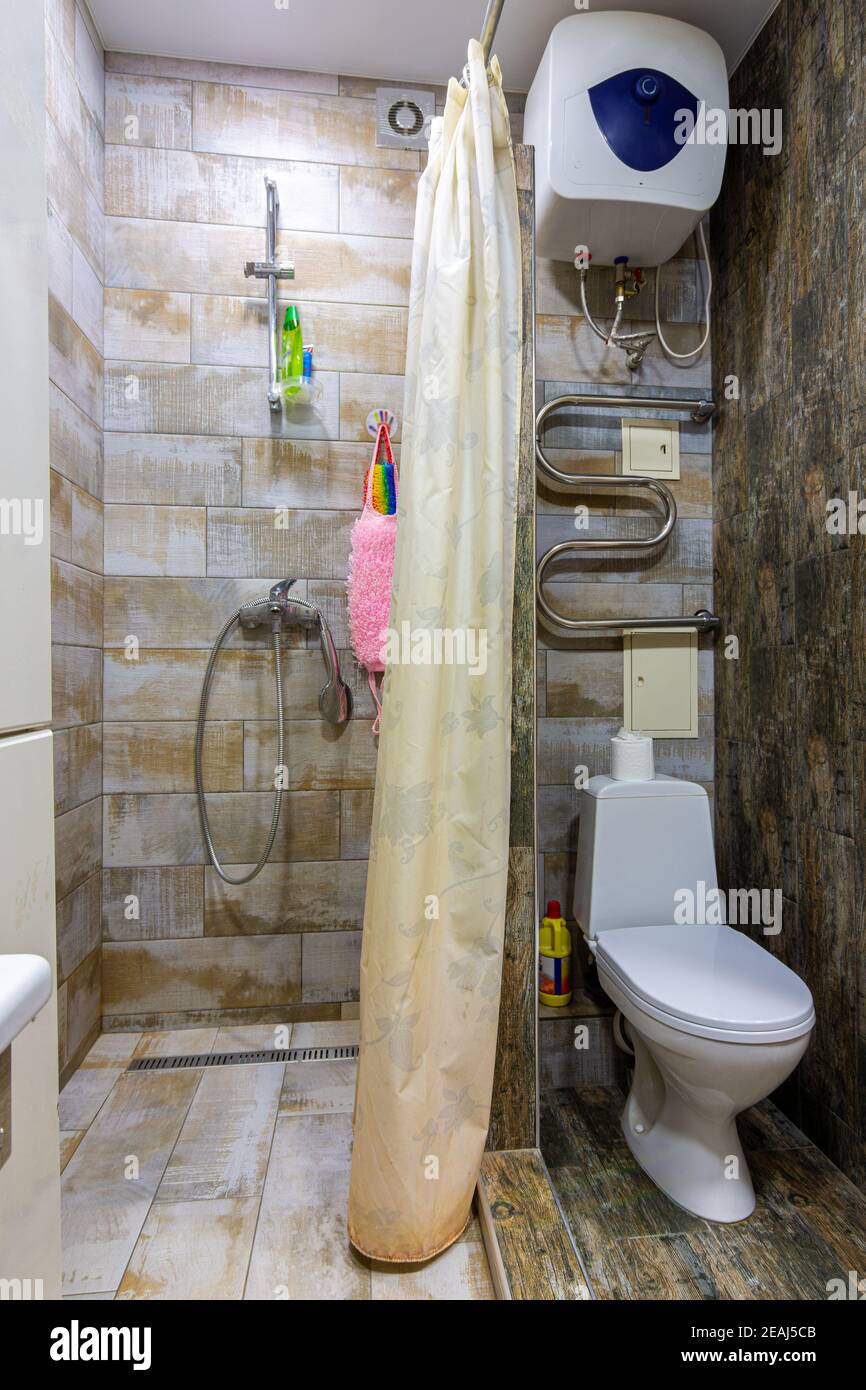 Kleines, kompaktes Badezimmer mit Duschvorhang und Toilette Stockfoto