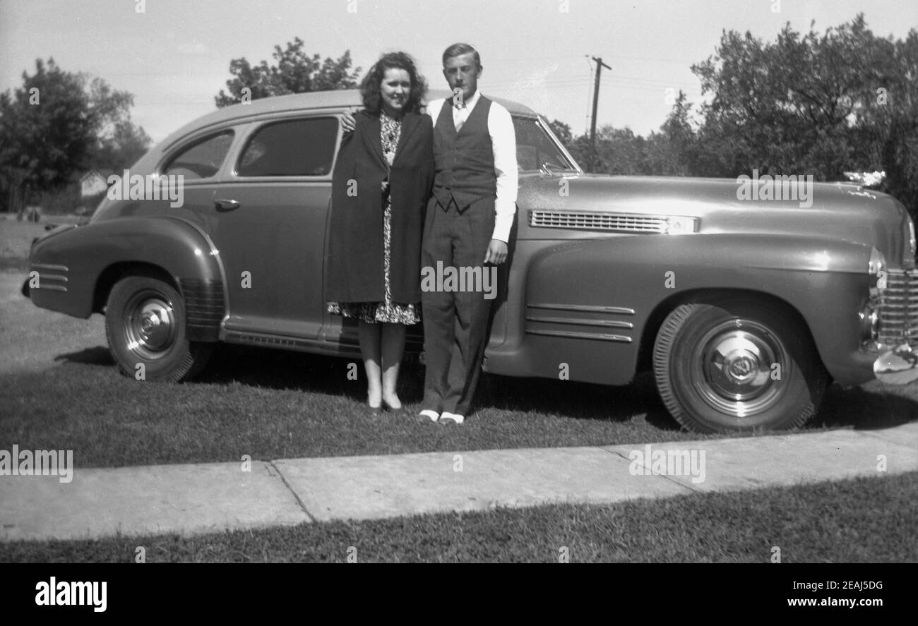 1945, historisch, ein Mann und seine Frau posieren für ein Foto neben seinem eleganten amerikanischen Auto geparkt auf einem Grasrand vor einem Haus, Oregon, USA. Stockfoto