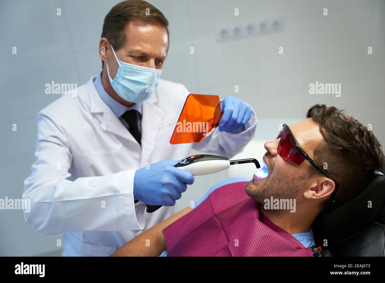 Fokussierter Zahnmediziner, der den Menschen mit Laser behandelt Stockfoto