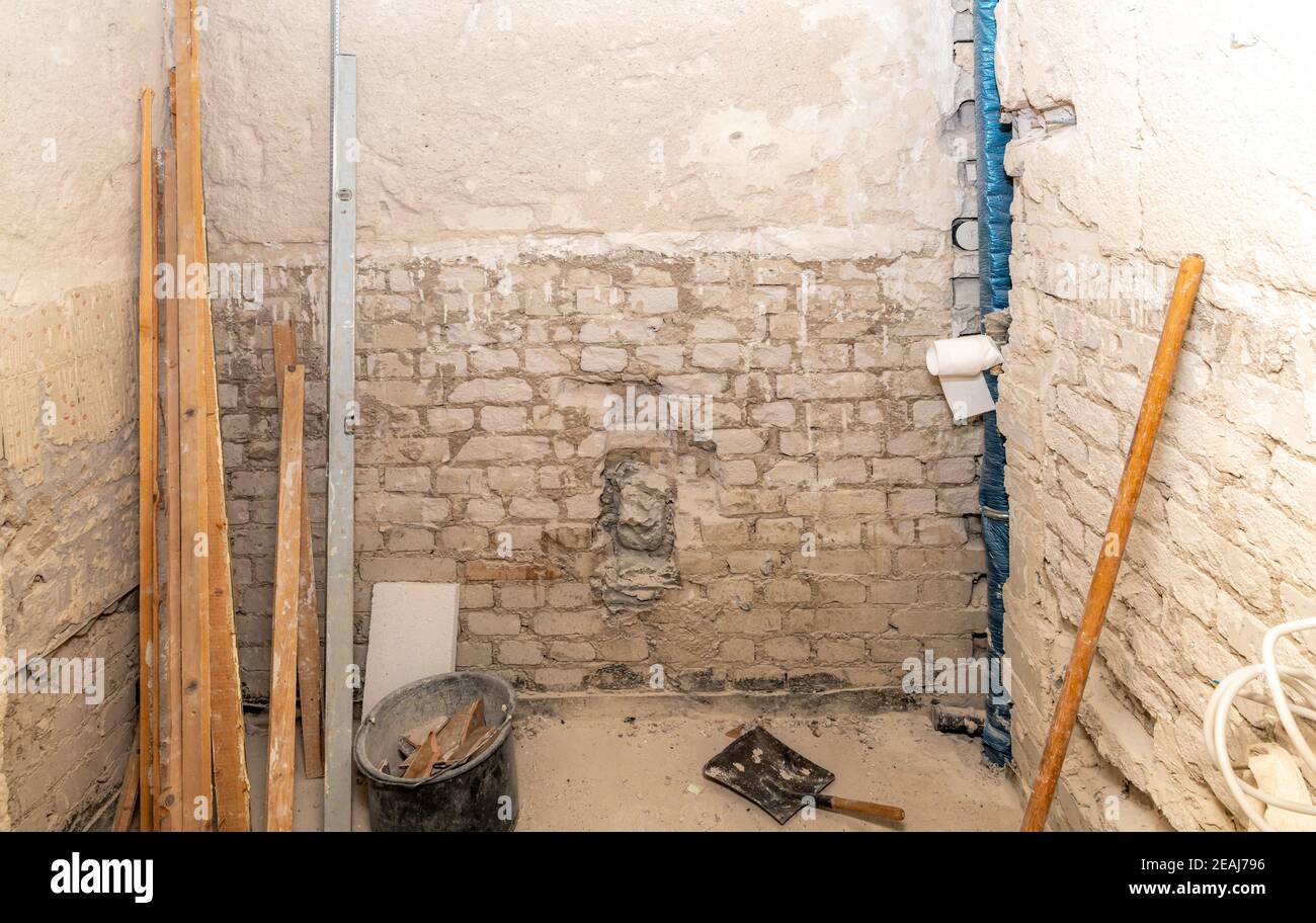 Baustelle eines Badezimmers im Bau mit Holzlatten, Wasserwaage, Eimer und Kehrschaufel Stockfoto