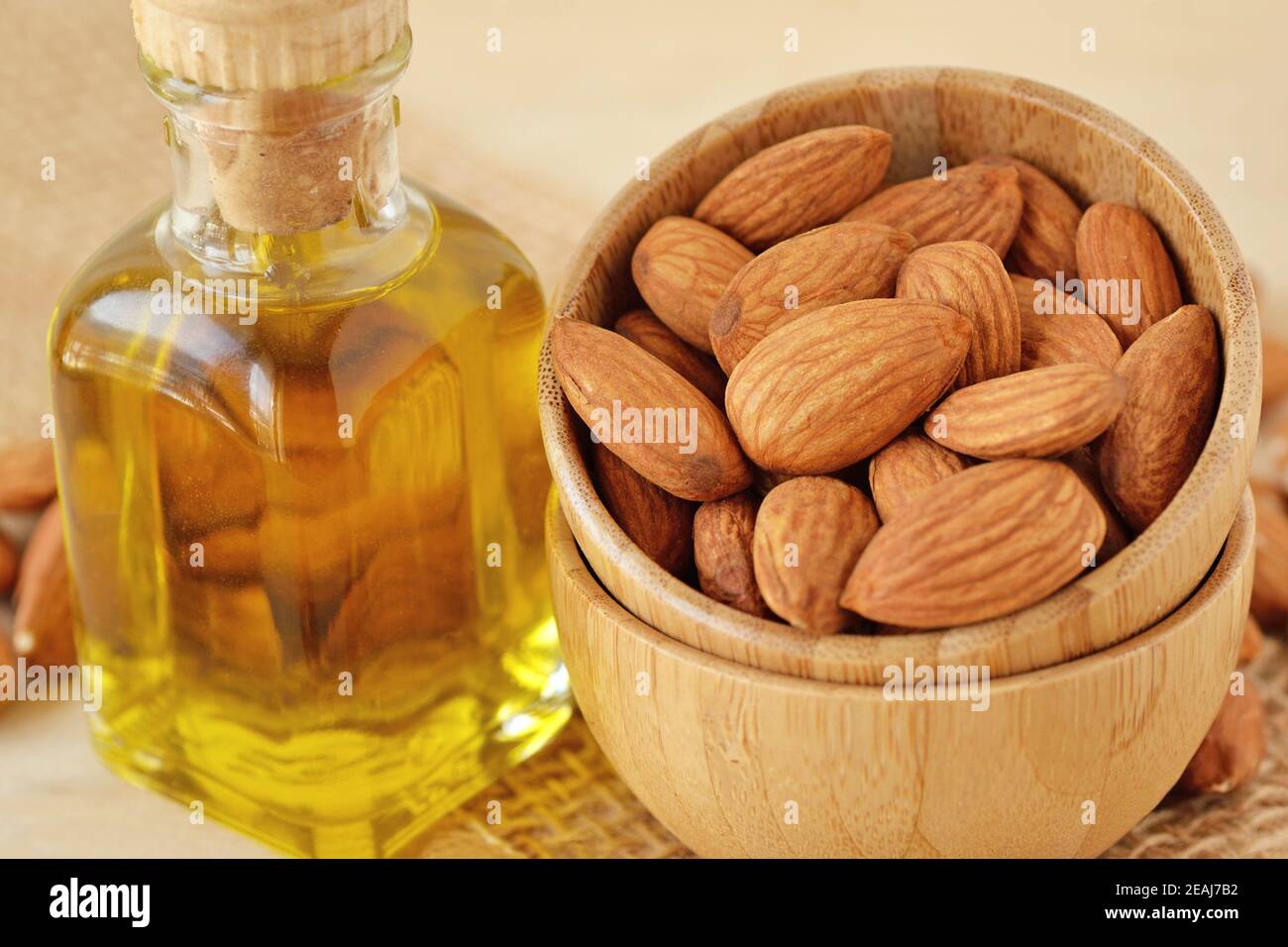 Flasche Mandelöl und Mandeln in Holzschüssel Stockfoto