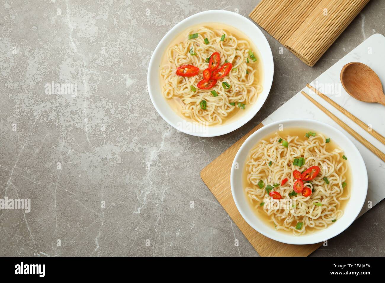 Konzept des leckeren Essens mit Schalen von Nudeln auf grau Hintergrund Stockfoto