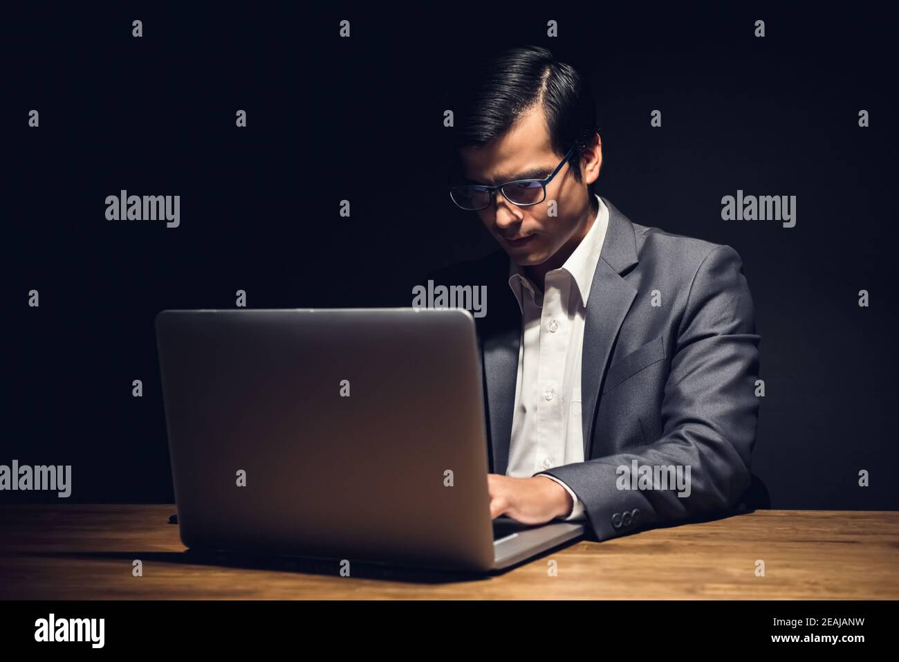 Fokussierter junger Geschäftsmann, der im Büro an Laptop-Computer-Überstunden arbeitet Nachts Stockfoto