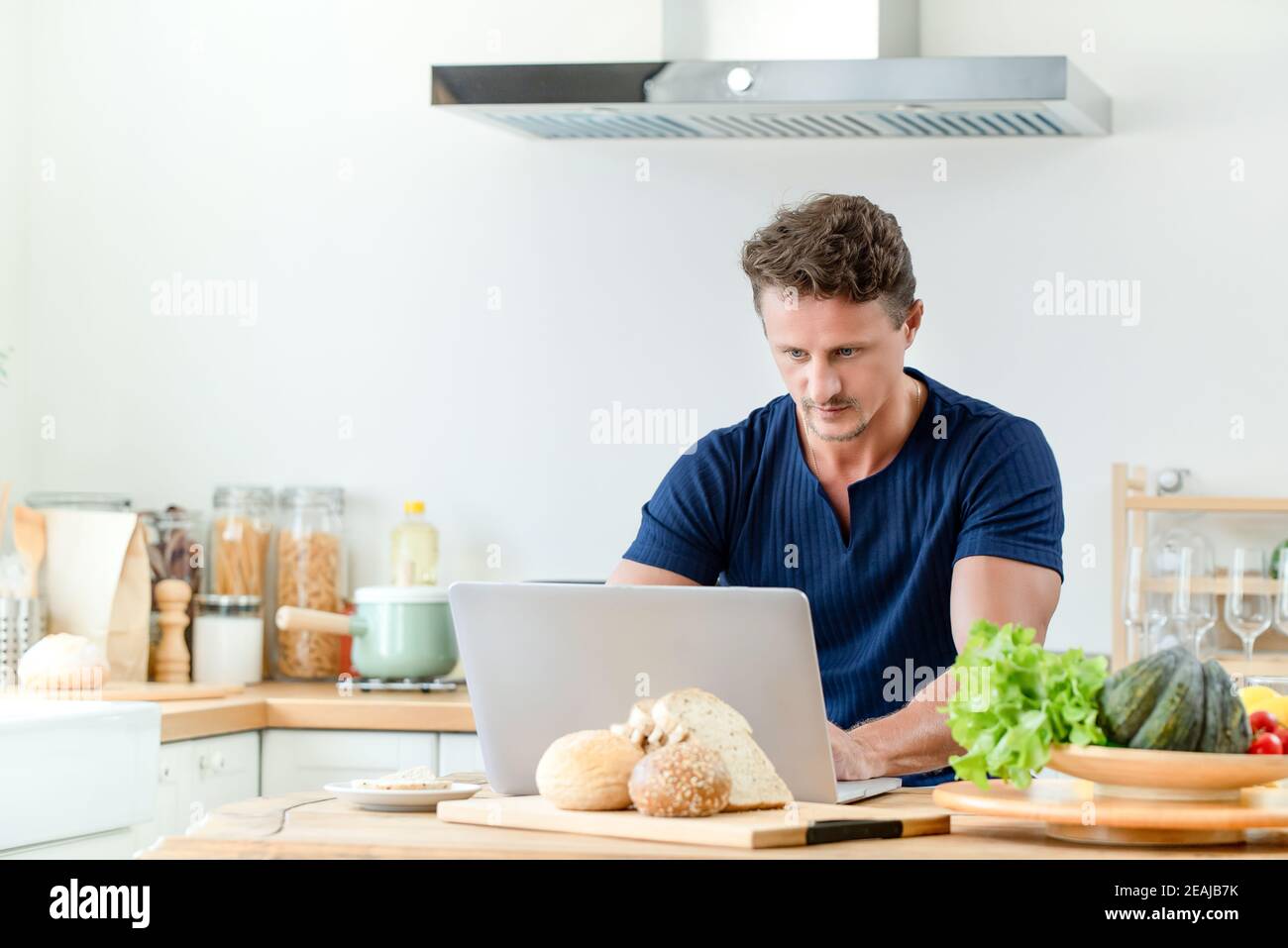 Schöner Mann mit Online-Chat und Arbeit von zu Hause aus Die Küche Stockfoto