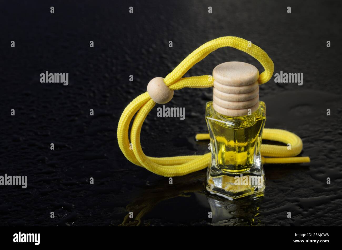 Eine Flasche gelbe Flüssigkeit mit einem Holzstopfen mit Wassertropfen auf einem schwarzen Holzhintergrund. Aromatische Öle. Selektiver Fokus. Stockfoto