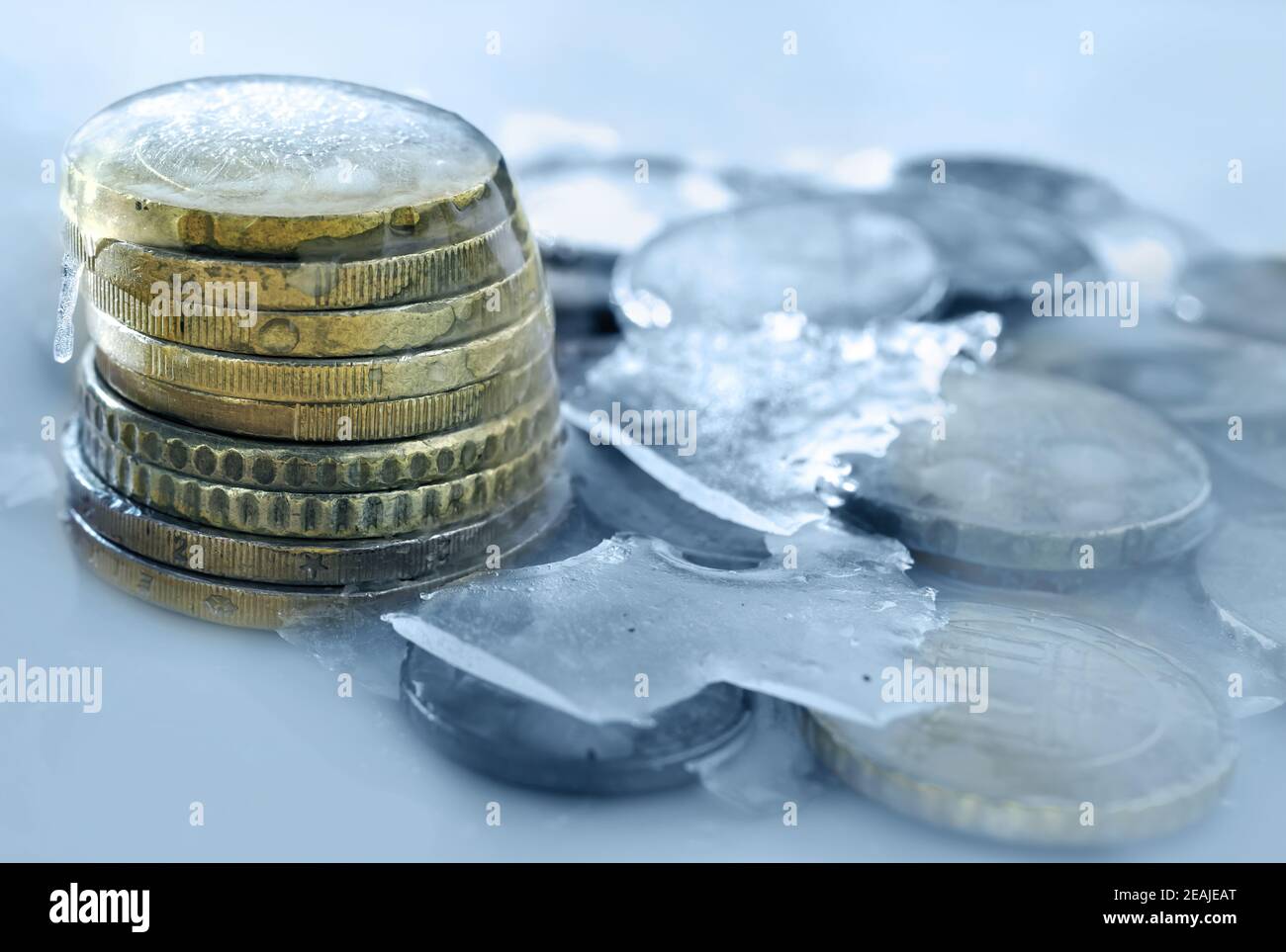 Im Eis eingefrorene Euro-Münzen. Gefrorenes Geld, Euro im Eis mit Eiszapfen Stockfoto