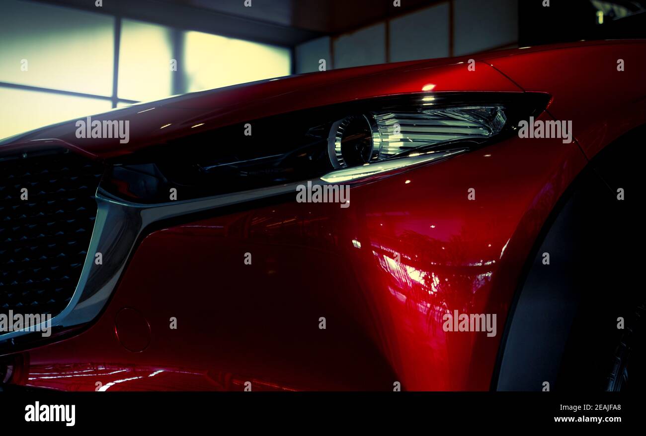 Nahaufnahme Scheinwerfer des neuen glänzenden roten Luxus-SUV-Auto. Elegante Elektroauto-Technologie und Geschäftskonzept. Hybrid Auto und Automotive Konzept. Auto im Ausstellungsraum oder in der Automobilausstellung geparkt. Autohaus. Stockfoto Nahaufnahme Scheinwerfer des neuen glänzenden roten Luxus-SUV-Auto. Elegante Elektroauto-Technologie und Geschäftskonzept. Hybrid Auto und Automotive Konzept. Auto im Ausstellungsraum oder in der Automobilausstellung geparkt. Autohaus. Stockfoto