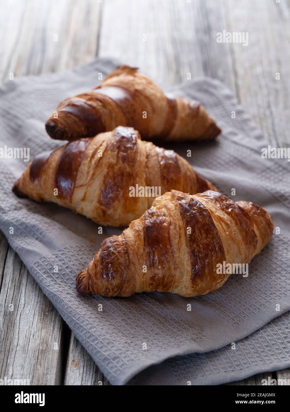 Croissant auf einem Tuch auf einem alten Holzhintergrund platziert Stockfoto