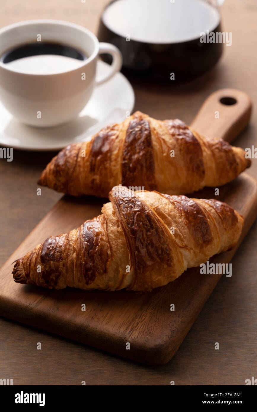 Croissants und Kaffee auf einem Holzbrett Stockfoto